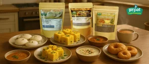 A collection of Zatpat Food Premix pouches — Idli, Dhokla, Dosa, Medu Vada, Kheer, and Jaggery Tea — neatly arranged on a kitchen table beside freshly prepared dishes.